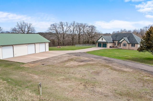 exterior space featuring a detached garage, fence, and a front yard