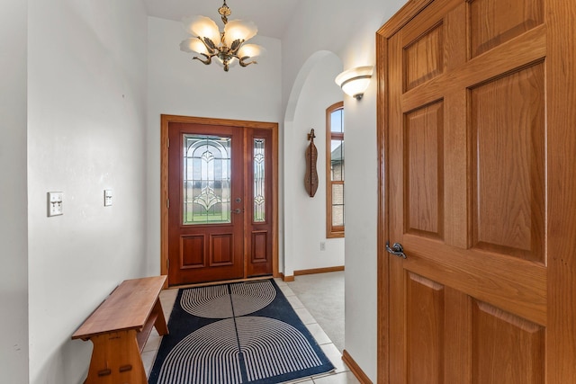 foyer entrance with baseboards, arched walkways, light tile patterned floors, and a notable chandelier