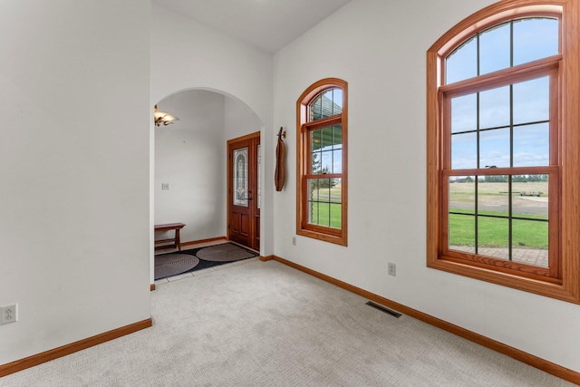 foyer with visible vents, arched walkways, baseboards, and a healthy amount of sunlight