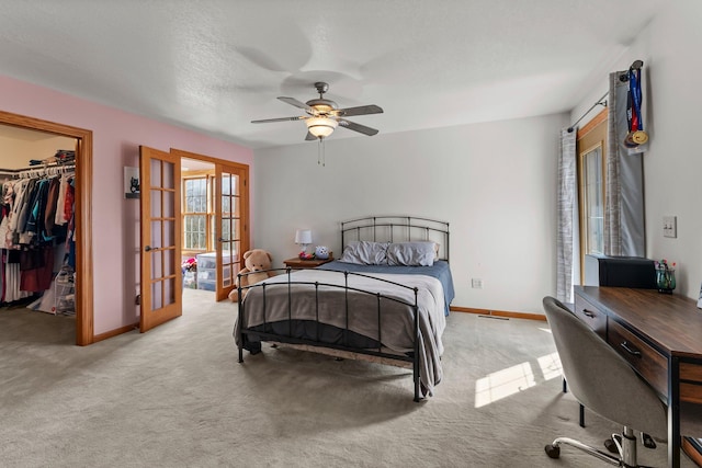 bedroom with baseboards, a walk in closet, french doors, and carpet