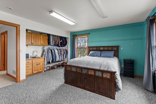 carpeted bedroom featuring visible vents, a sink, and a closet