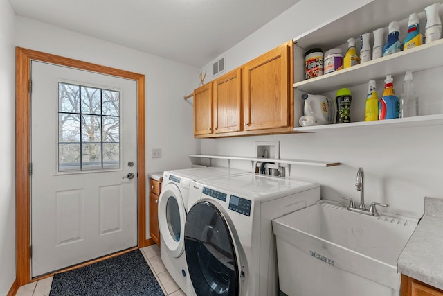 laundry room featuring visible vents, washing machine and dryer, cabinet space, a sink, and light tile patterned flooring
