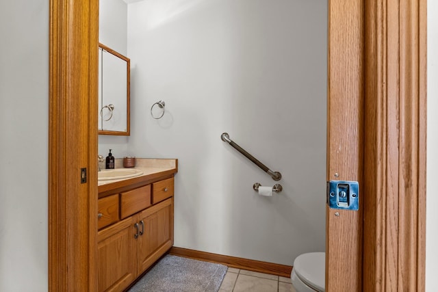 bathroom with vanity, baseboards, tile patterned floors, and toilet