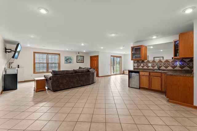 kitchen with dark countertops, brown cabinetry, open floor plan, decorative backsplash, and light tile patterned floors