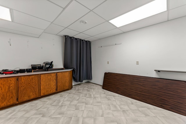 bar featuring light floors and a paneled ceiling