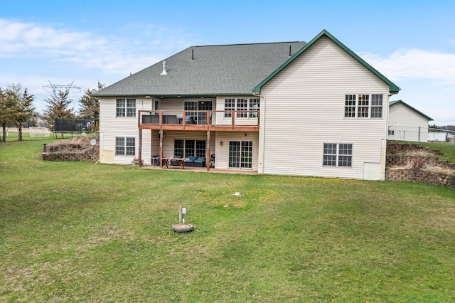 back of house with roof with shingles, a lawn, a wooden deck, a patio area, and fence