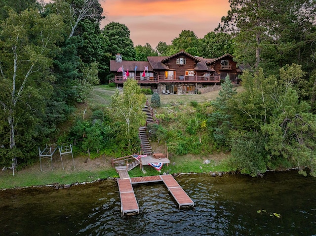 exterior space with stairs, a deck with water view, and a chimney