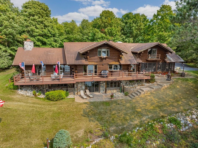 rear view of house with a lawn, a wooden deck, log exterior, and a chimney