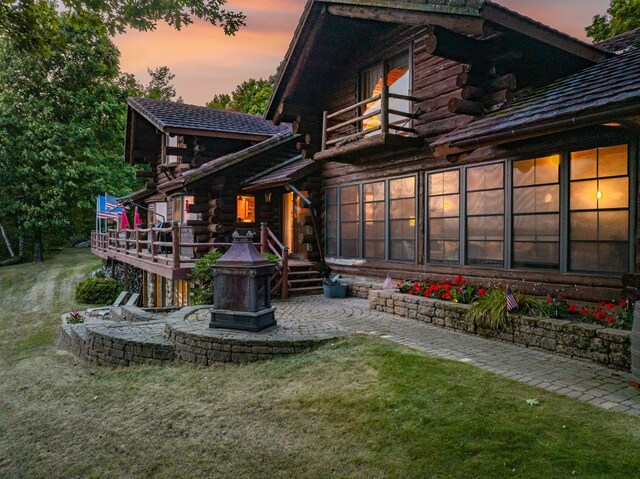rear view of house with a lawn, log siding, and a balcony