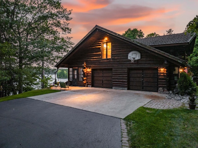 cabin featuring a yard, driveway, log siding, and a garage