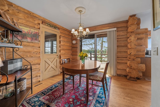 dining area featuring an inviting chandelier, rustic walls, and wood finished floors