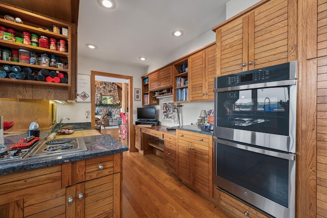 kitchen featuring open shelves, built in desk, brown cabinetry, stainless steel appliances, and recessed lighting