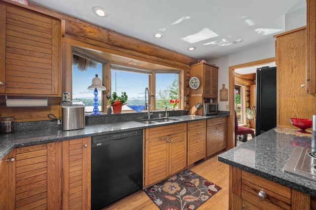 kitchen with a sink, brown cabinetry, black appliances, and a wealth of natural light