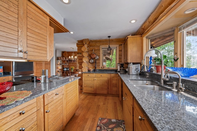kitchen with brown cabinetry, a sink, light wood-style floors, log walls, and recessed lighting