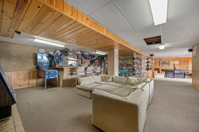 carpeted living area with billiards, a dry bar, wood walls, and a paneled ceiling