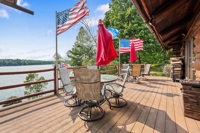 wooden terrace featuring outdoor dining space and a water view