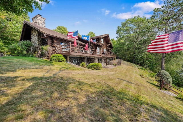 back of house with a chimney, a wooden deck, a yard, and log exterior