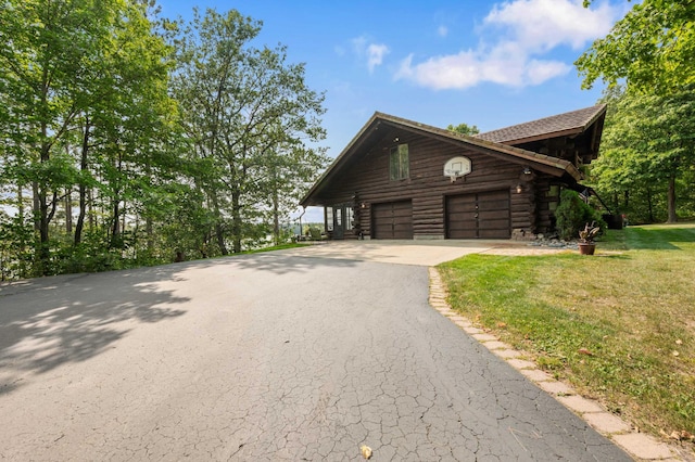 view of property exterior with an attached garage, a yard, driveway, and log siding