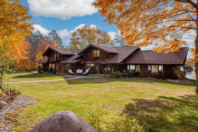 view of front of property featuring a patio, log exterior, and a front lawn