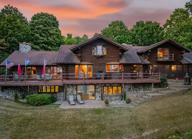 30047 Sunny Beach Rd, Grand Rapids, MN 55744 - back of house at dusk featuring log exterior, a chimney, a yard, and stone siding