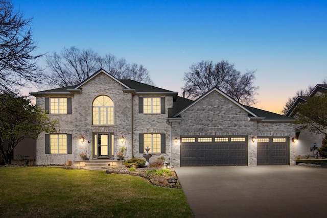 view of front of home with driveway, an attached garage, a lawn, and brick siding