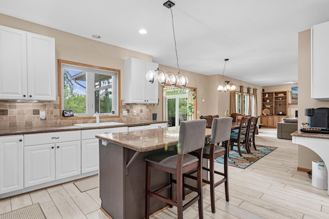 14217 Footbridge Way, Apple Valley, MN 55124 - kitchen with tasteful backsplash, white cabinetry, stone counters, hanging light fixtures, and light wood finished floors