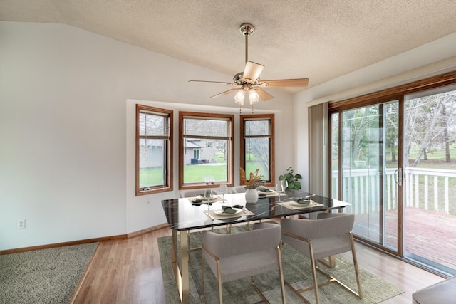 dining area featuring a ceiling fan, a textured ceiling, baseboards, light wood finished floors, and lofted ceiling