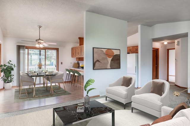 living room featuring baseboards, light wood finished floors, ceiling fan, and lofted ceiling