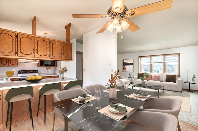 dining space with a ceiling fan, vaulted ceiling, and light wood-style flooring