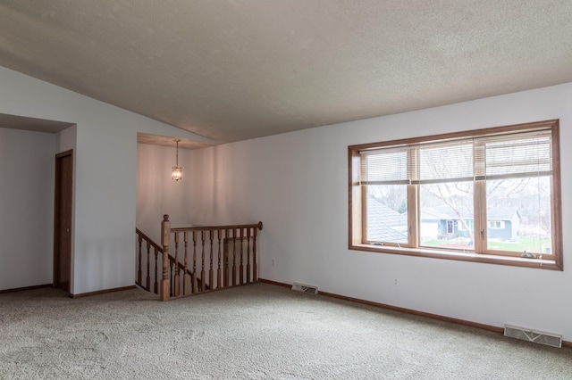 spare room with carpet flooring, baseboards, visible vents, and vaulted ceiling