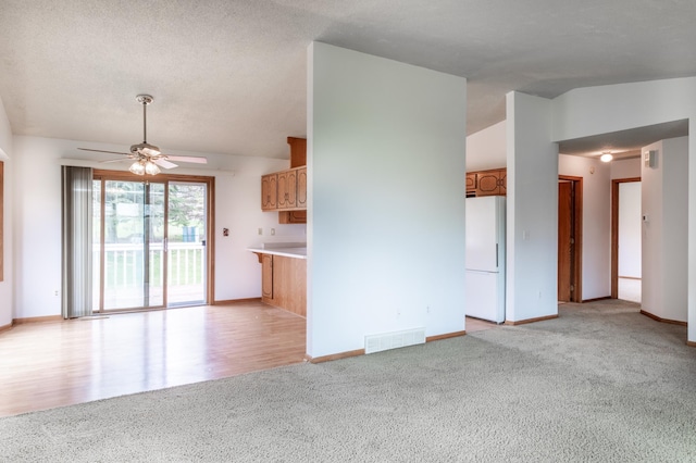 unfurnished living room with baseboards, ceiling fan, light colored carpet, and visible vents