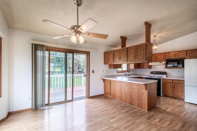 kitchen with freestanding refrigerator, a peninsula, black microwave, range with electric stovetop, and under cabinet range hood