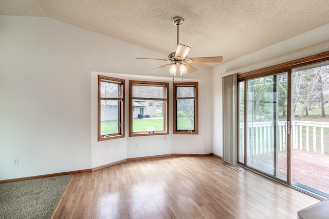 unfurnished room with wood finished floors, baseboards, a textured ceiling, a ceiling fan, and vaulted ceiling