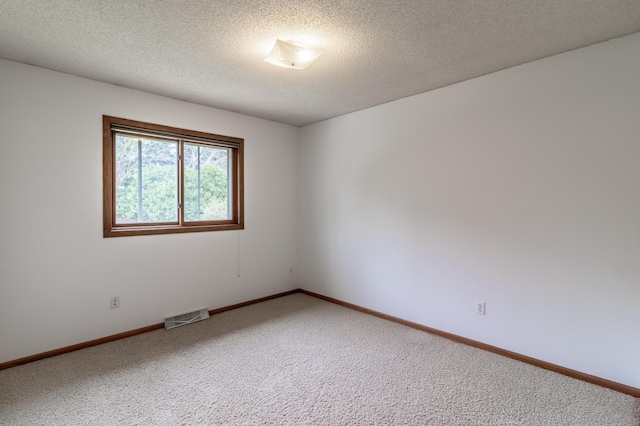 carpeted spare room with visible vents, a textured ceiling, and baseboards