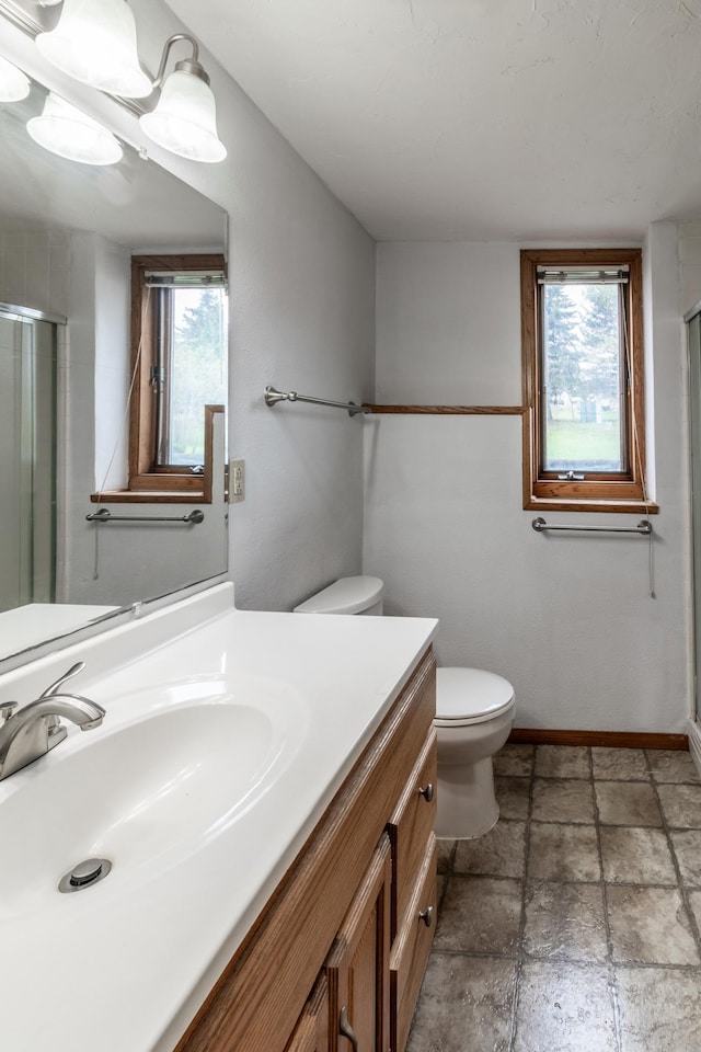 full bathroom with vanity, stone tile floors, toilet, and a shower stall
