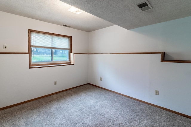 carpeted spare room with baseboards, a textured ceiling, and visible vents