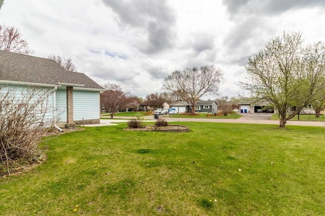 view of yard featuring driveway, a residential view, and a carport