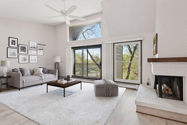 9600 Portland Ave S Unit 322, Bloomington, MN 55420 - living area with wood finished floors, a ceiling fan, a baseboard radiator, a towering ceiling, and a brick fireplace