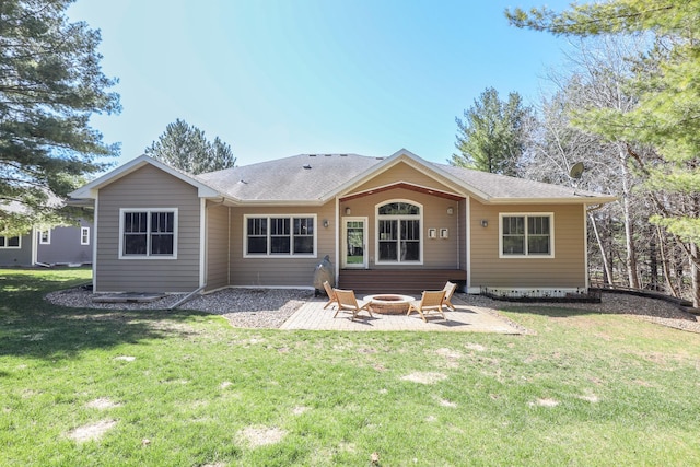 rear view of property with a yard, roof with shingles, a fire pit, and a patio area