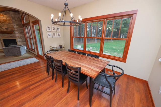 dining area featuring baseboards, wood finished floors, a chandelier, and a fireplace
