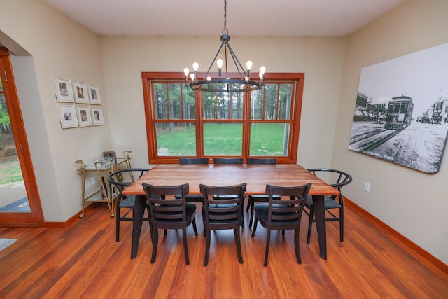 dining area with baseboards, wood finished floors, and a chandelier