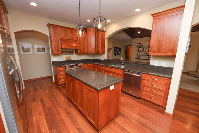 kitchen featuring appliances with stainless steel finishes, a sink, arched walkways, dark wood finished floors, and recessed lighting