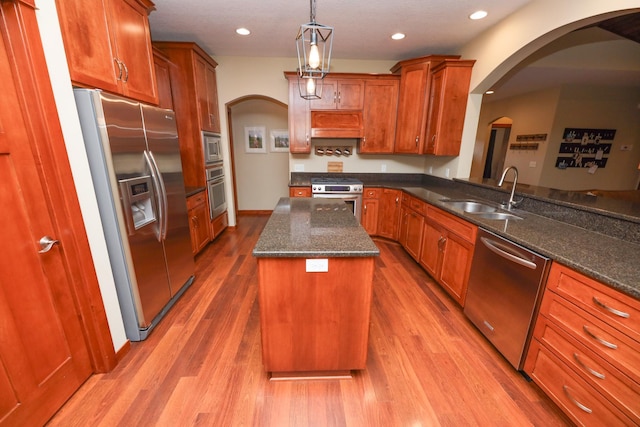 kitchen featuring brown cabinetry, a center island, a sink, stainless steel appliances, and recessed lighting