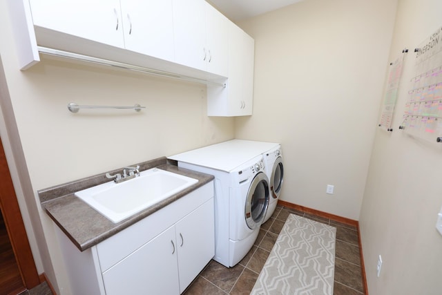 laundry area featuring cabinet space, a sink, baseboards, dark tile patterned flooring, and washer and dryer