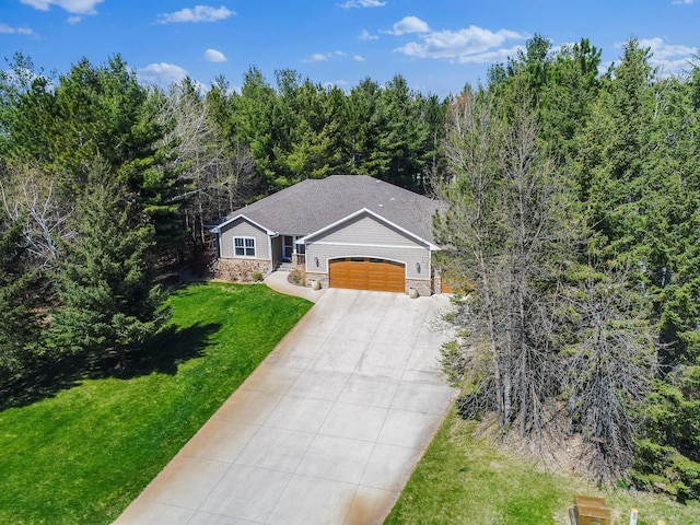 view of front facade featuring an attached garage, stone siding, driveway, a front lawn, and a forest view