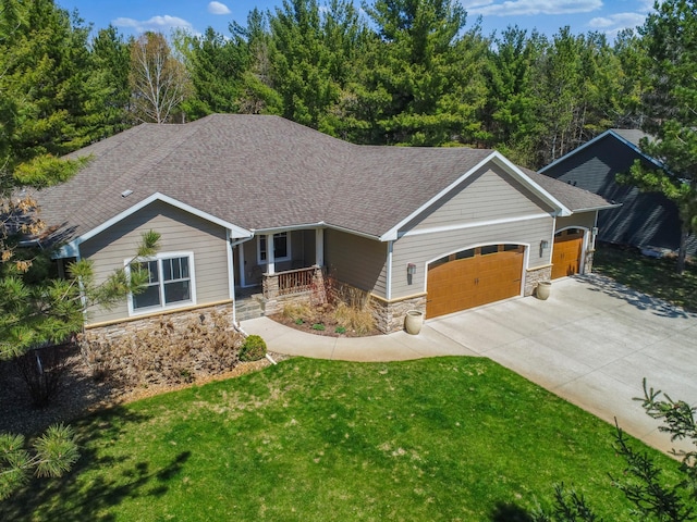 view of front of home featuring covered porch, a garage, stone siding, and a front yard