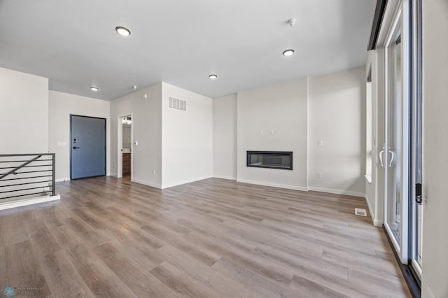 unfurnished living room with recessed lighting, baseboards, light wood-type flooring, and visible vents