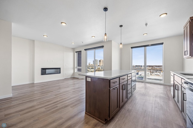 kitchen with dark brown cabinetry, decorative light fixtures, dishwasher, light countertops, and light wood-style flooring