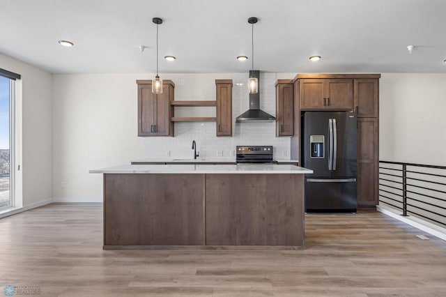 kitchen with wall chimney range hood, backsplash, light countertops, a sink, and stainless steel appliances