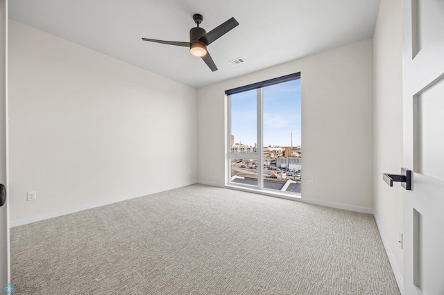 carpeted empty room with visible vents, baseboards, and ceiling fan